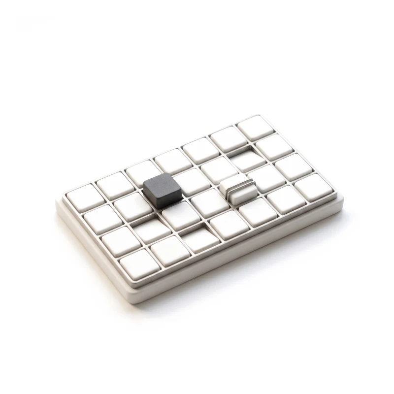 A ceramic calendar grid in a steel frame, some tiles pressed down, one graphite, one clipped.