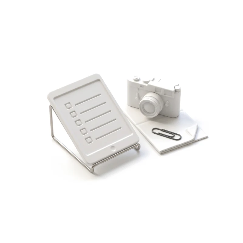 A ceramic tablet on a steel stand carved with a checklist, a ceramic camera and a document with a graphite clip beside it.