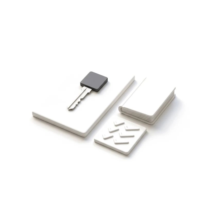 A steel key with a graphite head on a ceramic slab, a closed ceramic booklet and a small tile of raised checks beside it.