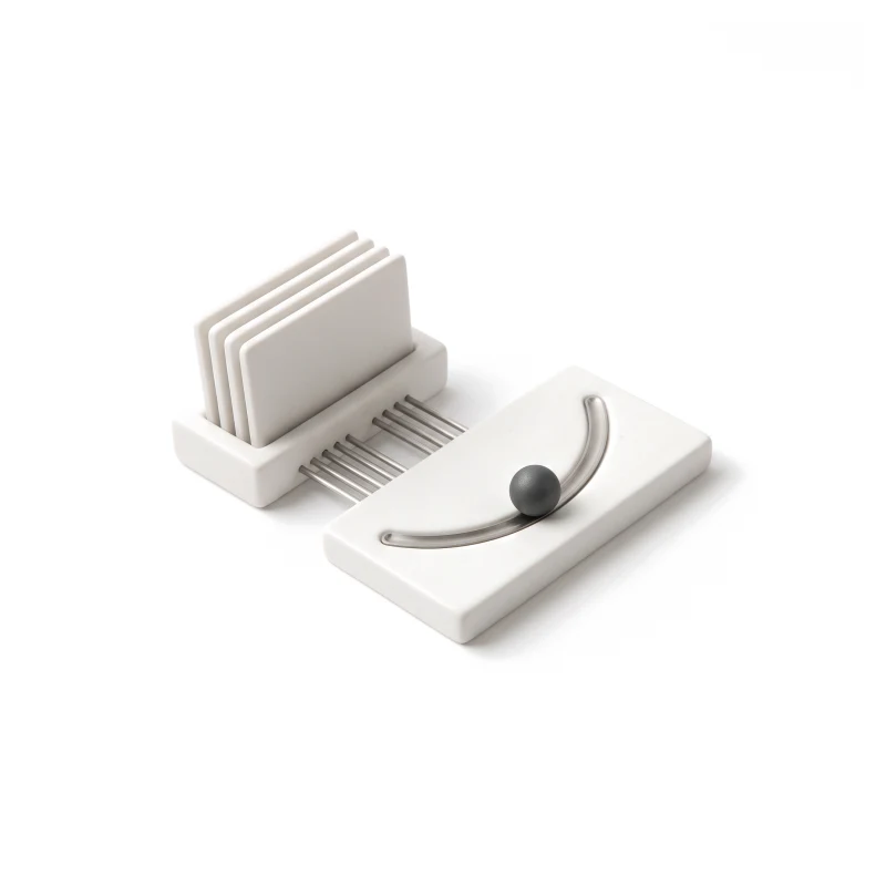 A ceramic holder of identical cards beside a flat ceramic slab with a curved steel track and a graphite ball resting on it.