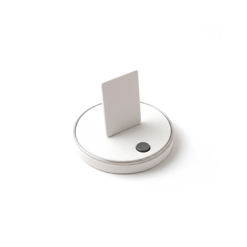 An upright ceramic page tile on a round ceramic turntable with a steel rim and a graphite push button in its base.