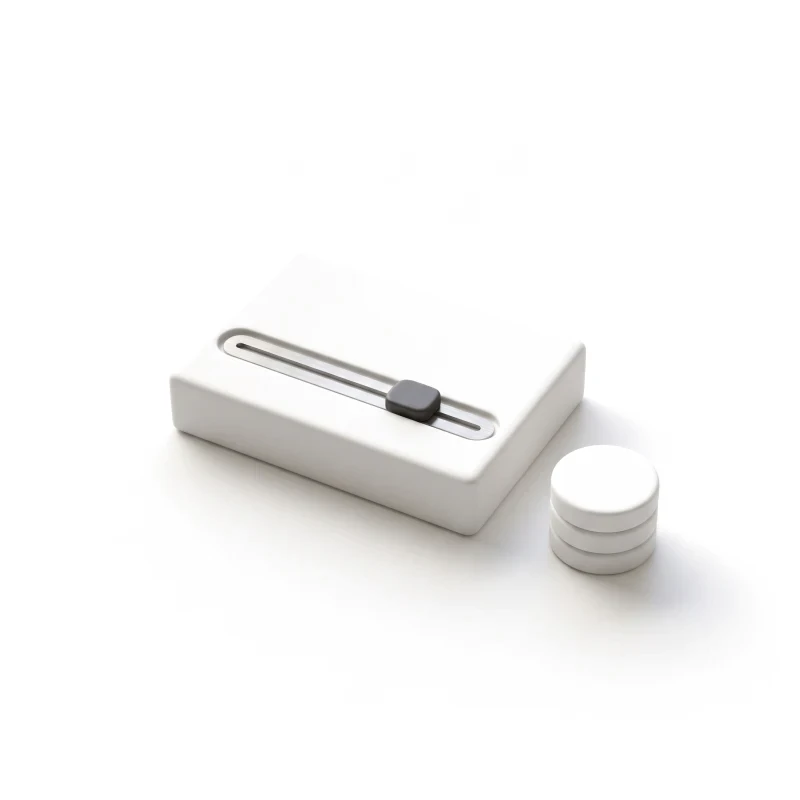 A ceramic block with a brushed-steel slider track and a graphite knob two thirds along it, a short stack of ceramic discs beside it.
