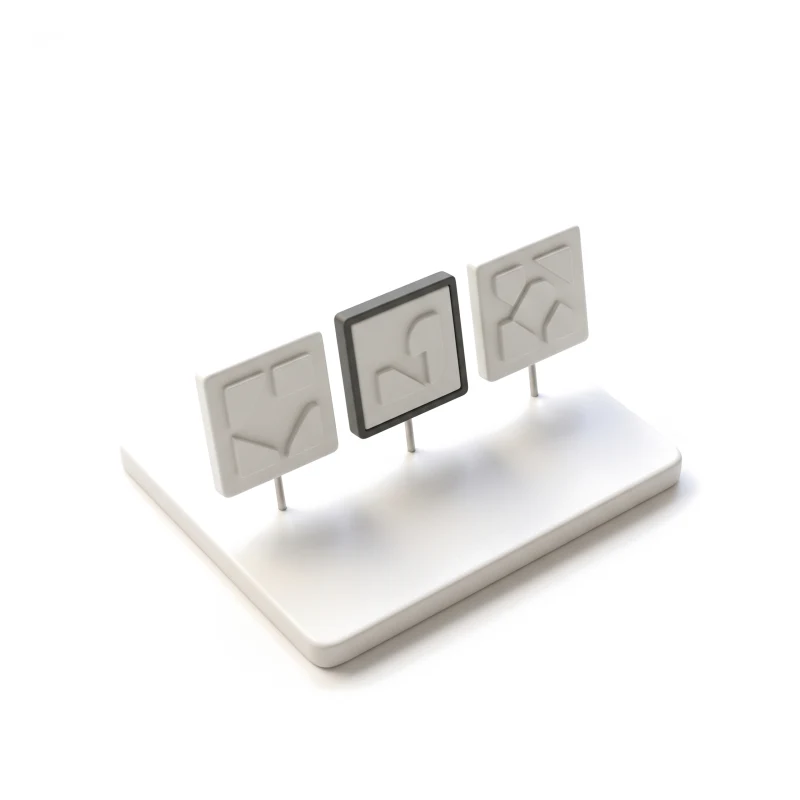 A white ceramic plinth holding three square relief tiles on steel pins, the middle one framed in graphite.