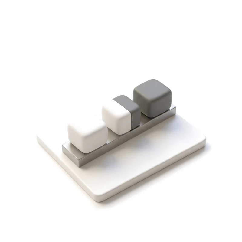 Three ceramic blocks on a short steel rail on a white base, the first white, the second half graphite, the last fully graphite.