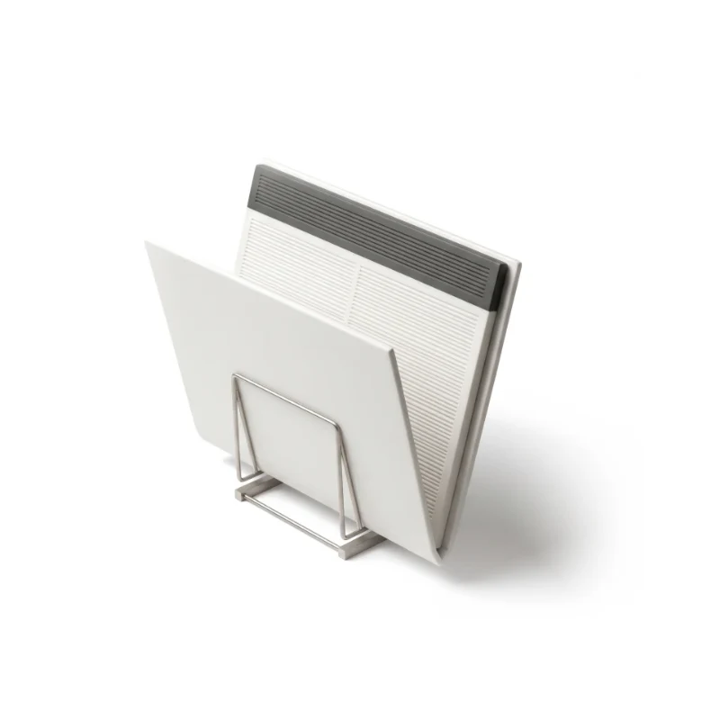A half-open white ceramic folder of fine carved rows on a steel stand, the summary band at the top in graphite.