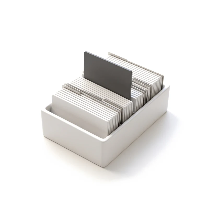 A ceramic card index box full of upright ceramic cards on steel dividers, one card lifted higher in graphite.