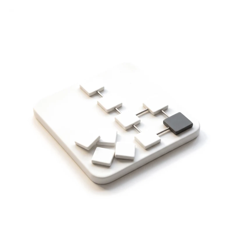 White ceramic tiles joined by steel rods into one path ending in a graphite tile, other tiles set aside.