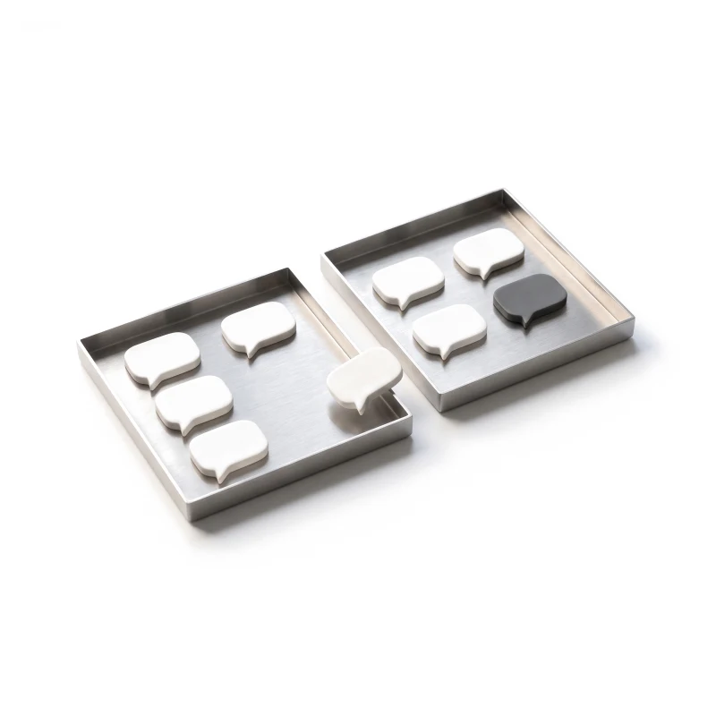 White ceramic speech bubbles sorted into two steel trays, one bubble graphite.