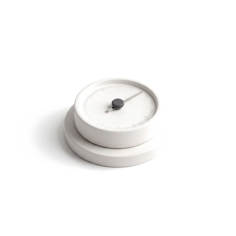 A round white ceramic gauge with carved ticks, a thin steel needle and a graphite centre knob.